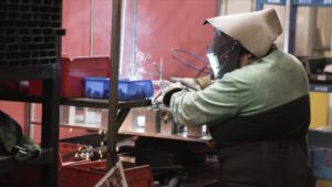 man wearing a facemask working on a machine.
